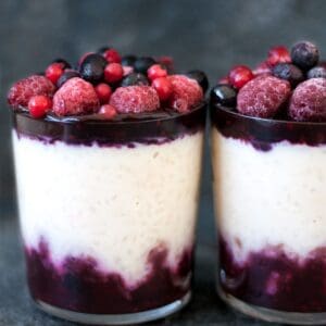 rice pudding in a glass topped with berry sauce and fresh berries