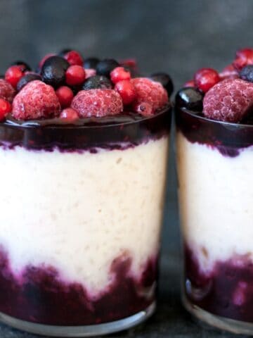 rice pudding in a glass topped with berry sauce and fresh berries