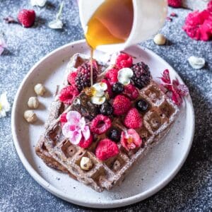 chocolate waffles topped with berries and drizzled with maple syrup