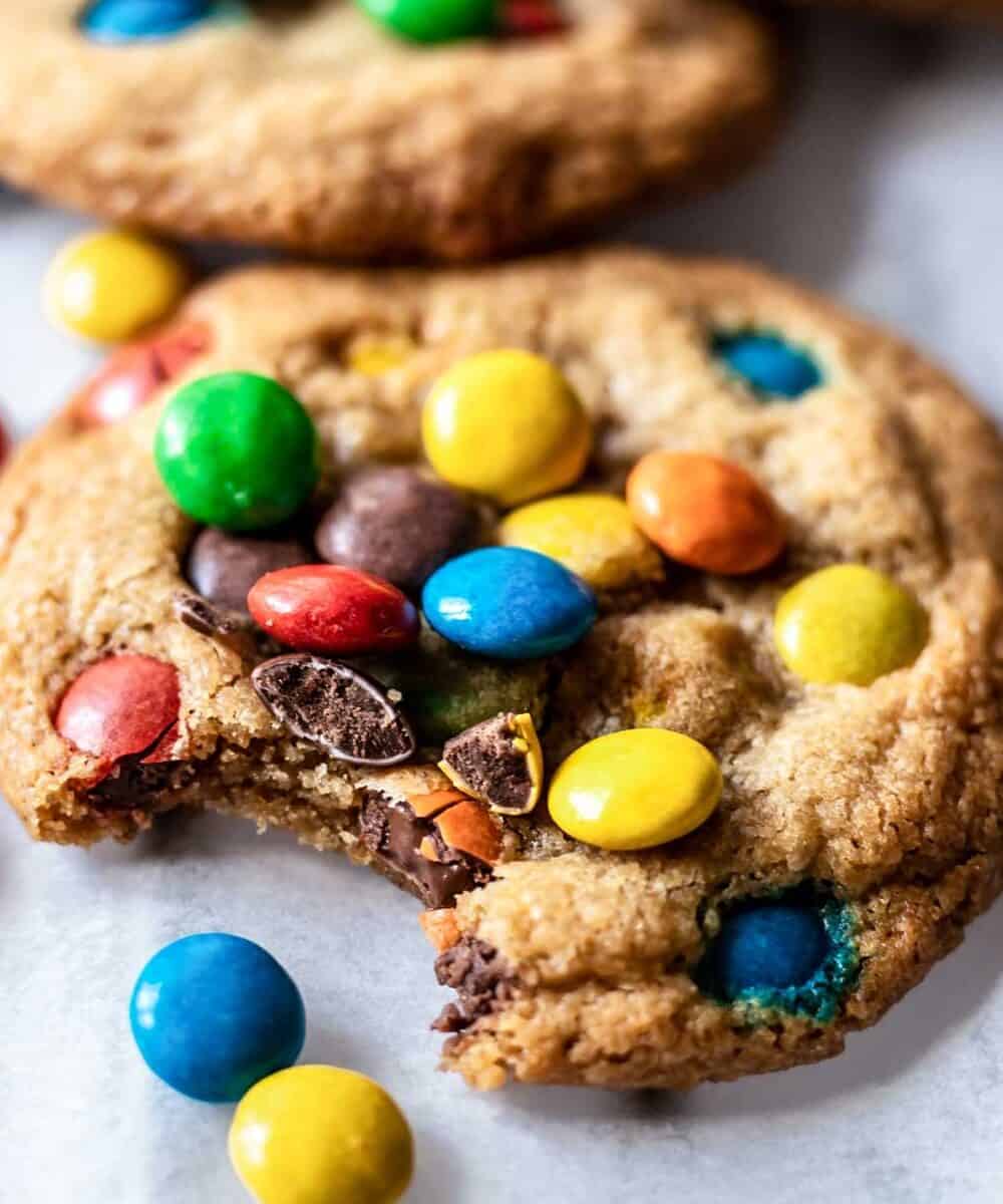 gluten free m&m cookies with a bite taken out to show the texture of the cookie.