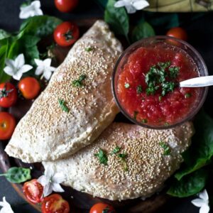 two gluten-free calzones served with tomato sauce