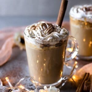 Pumpkin latte in a glass decorated with whipped cream and cinnamon stick
