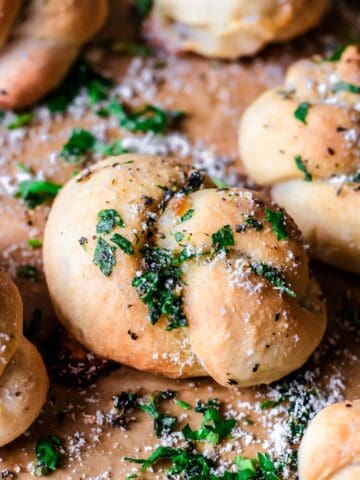 Freshly baked gluten-free garlic knots sprinkled with parsley and parmesan cheese