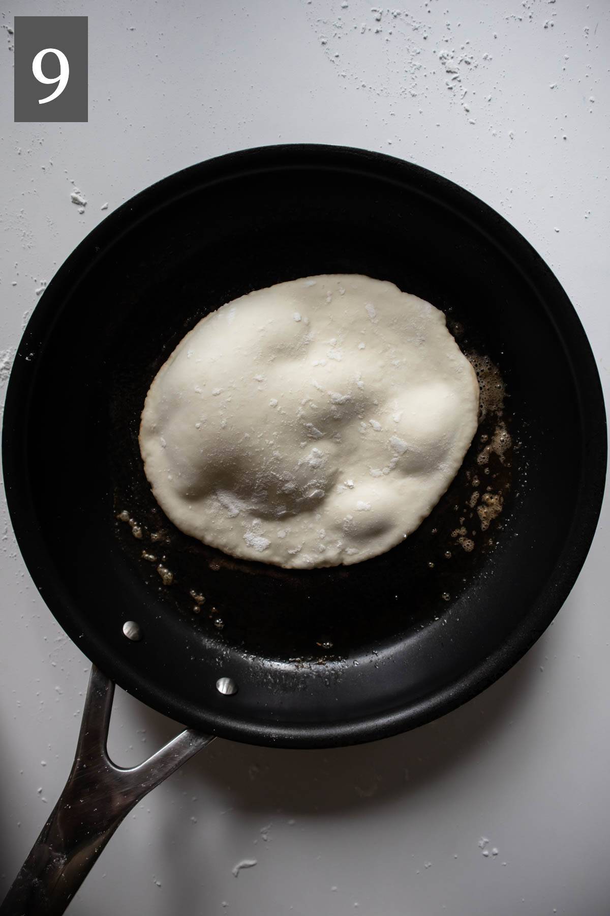 Frying naan dough in a cast iron skillet.