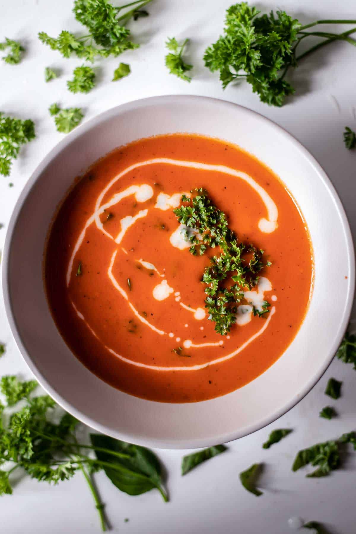 Gluten-free tomato soup in a bowl decorated with cooking cream and fresh parsley 