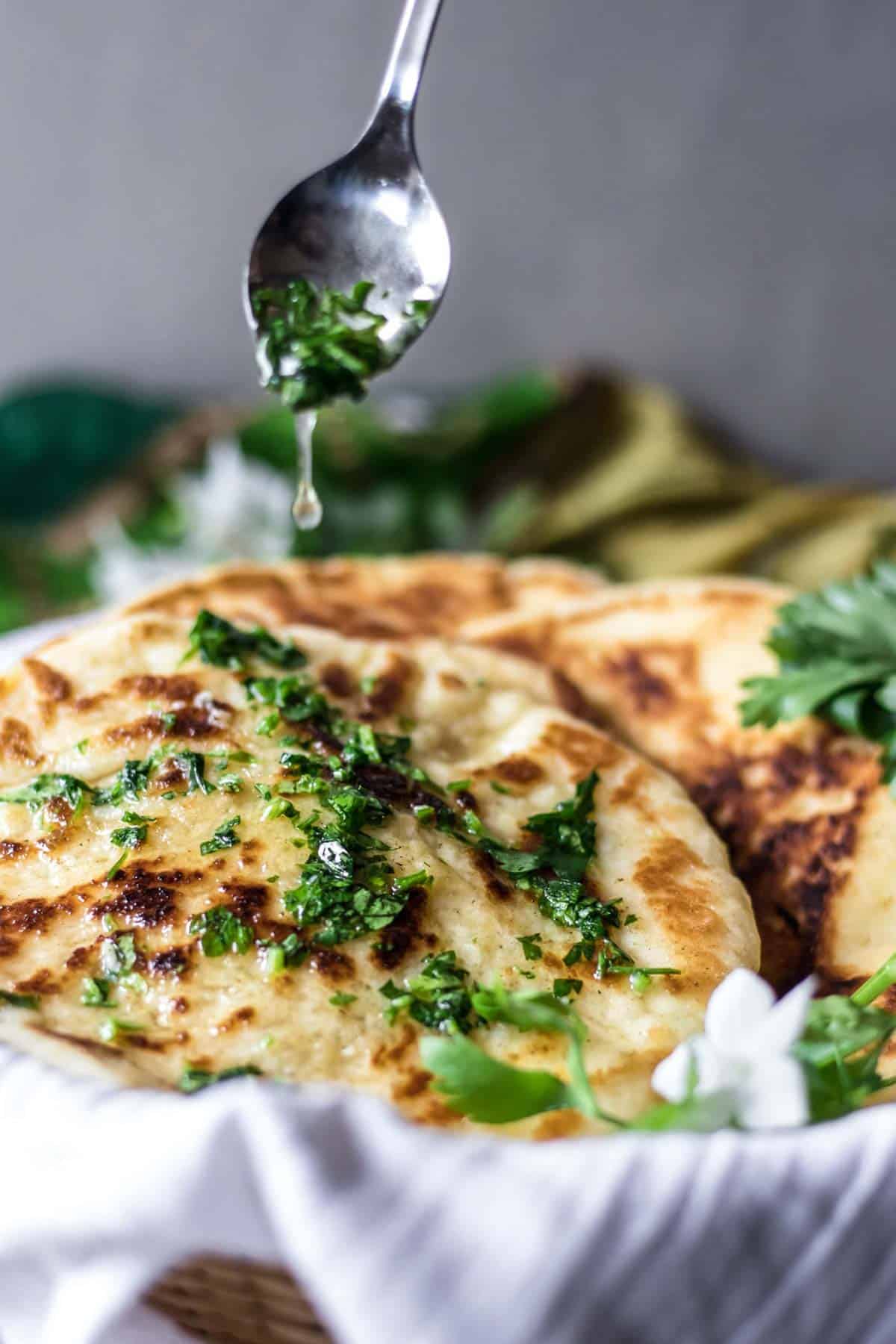 Adding garlic butter over gluten-free naan bread.