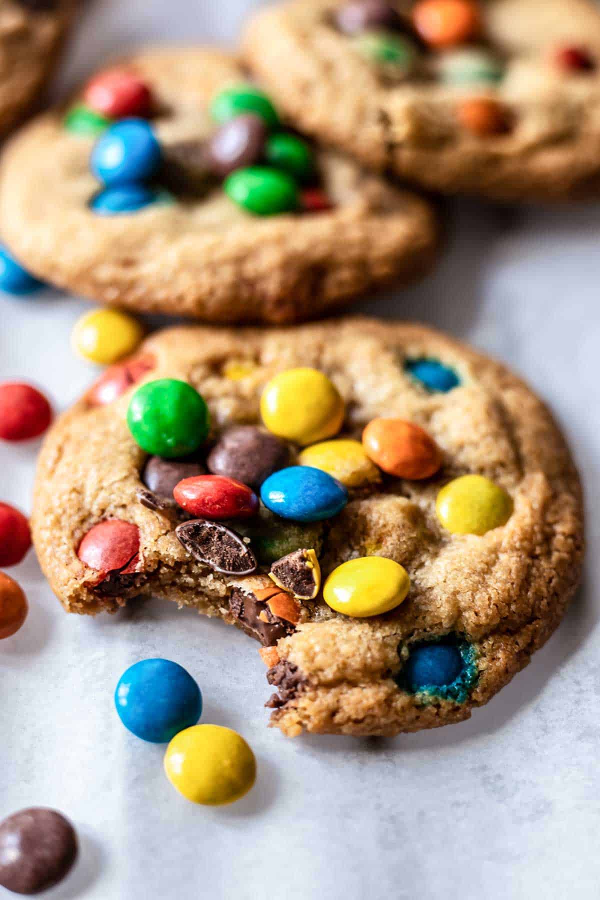 gluten free m&m cookies with a bite taken out to show the texture of the cookie.