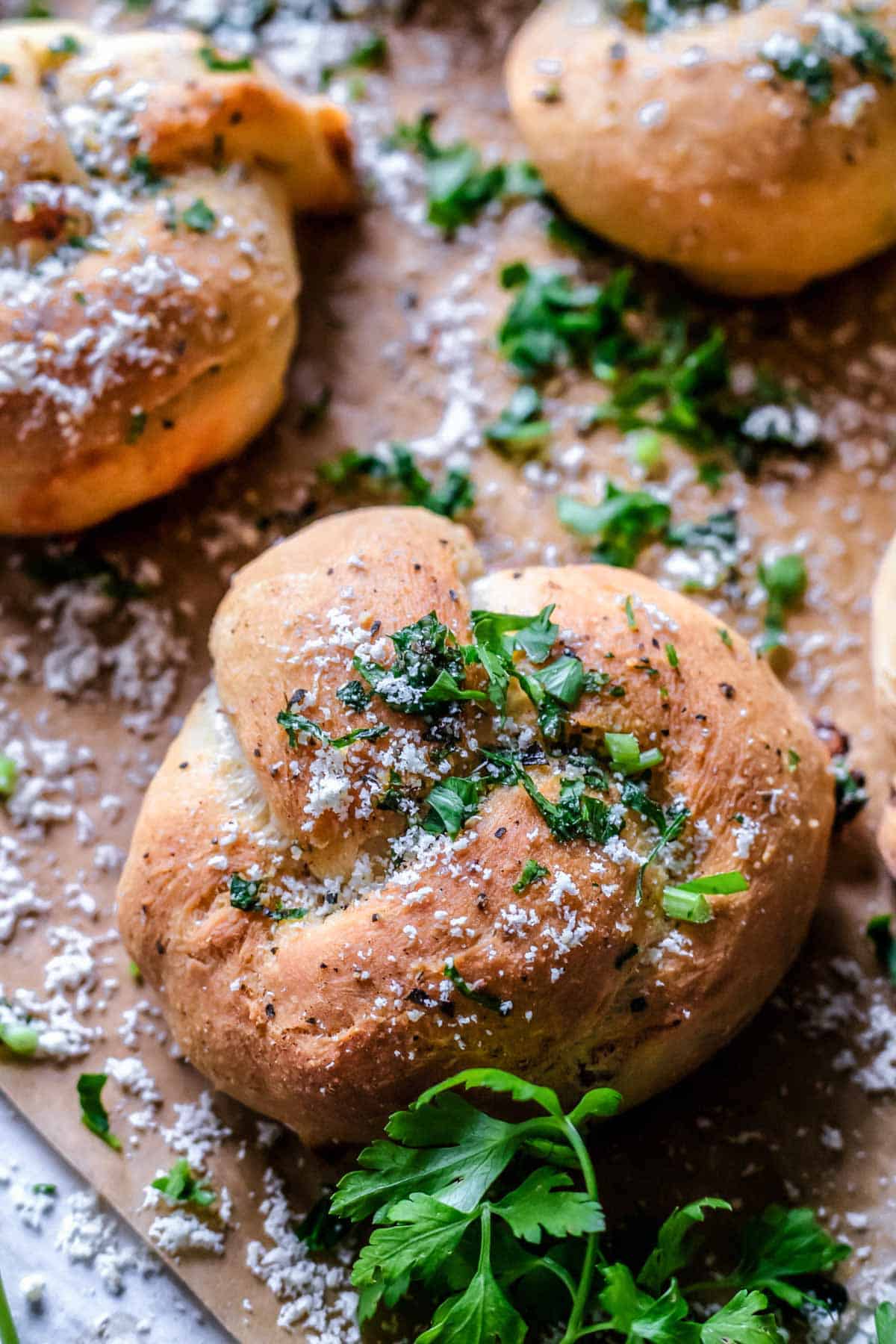 Garlic knot sprinkled with parmesan cheese and fresh parsley
