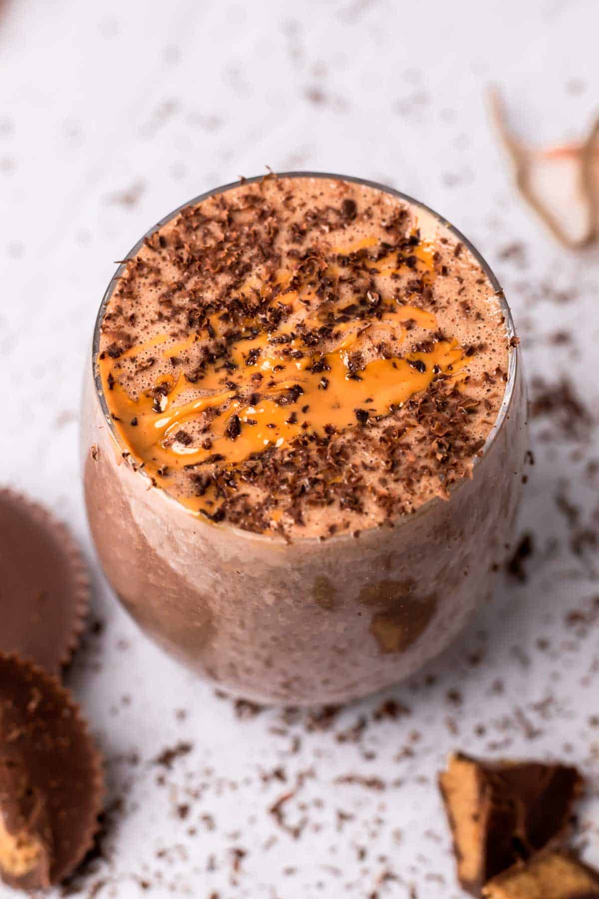 Peanut butter cup tropical smoothie in a glass decorated with peanut butter and shredded chocolate