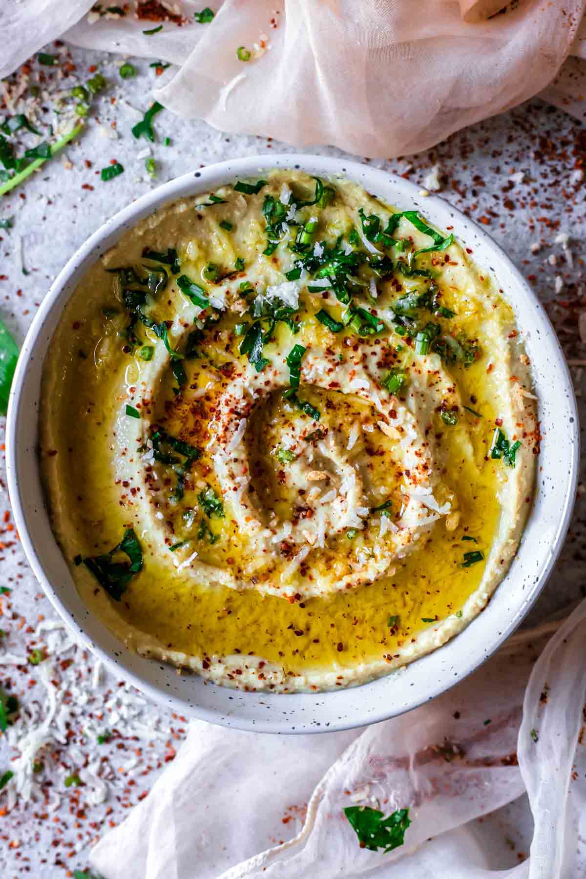 A bowl of hummus drizzled with olive oil and sprinkled with parsley