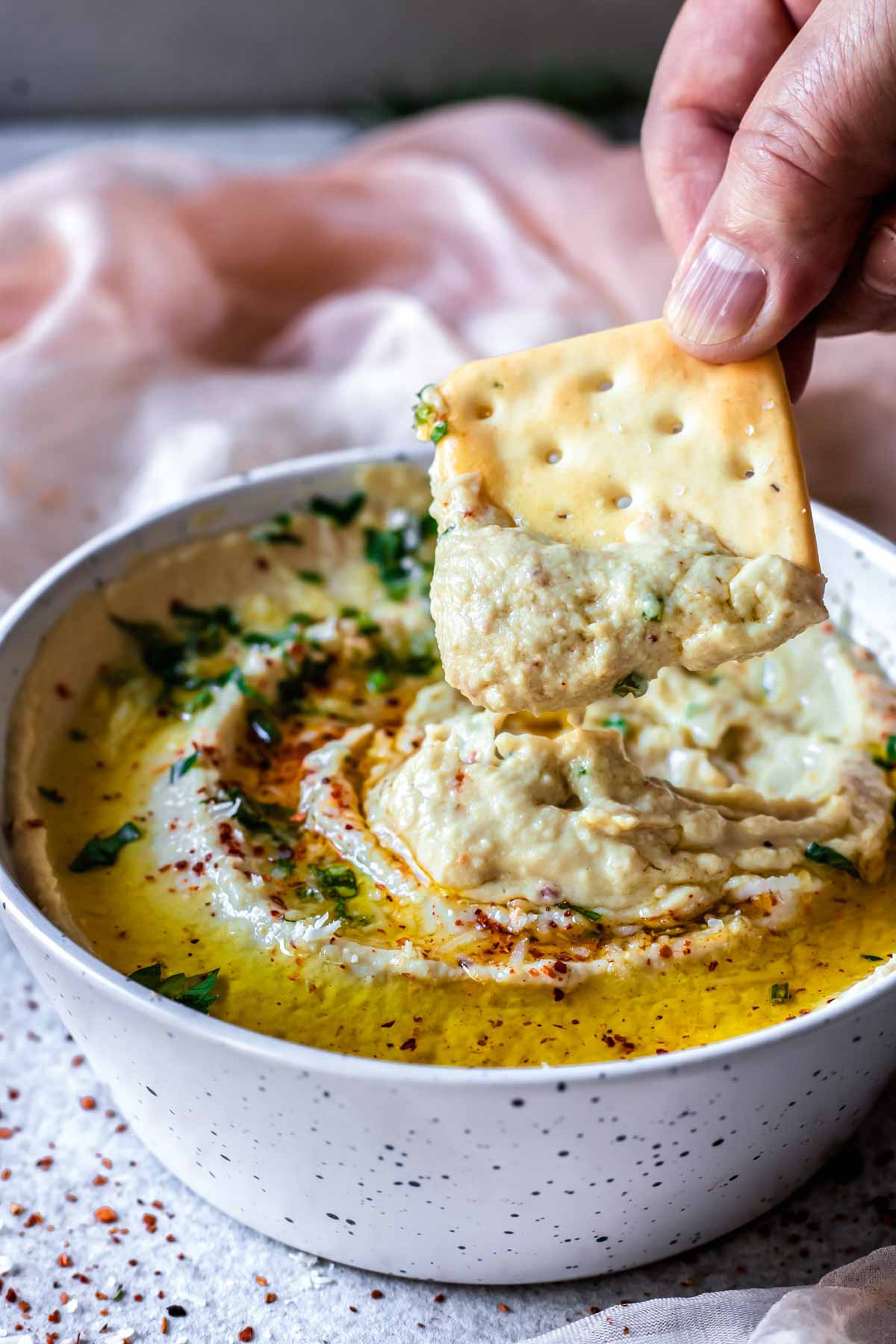 Scooping low fodmap hummus with a cracker.