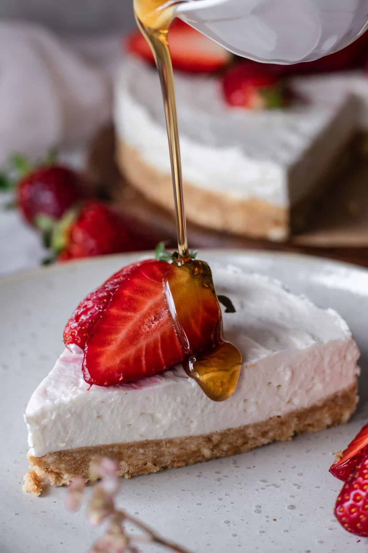 Pouring maple syrup over a slice of no-bake cheesecake