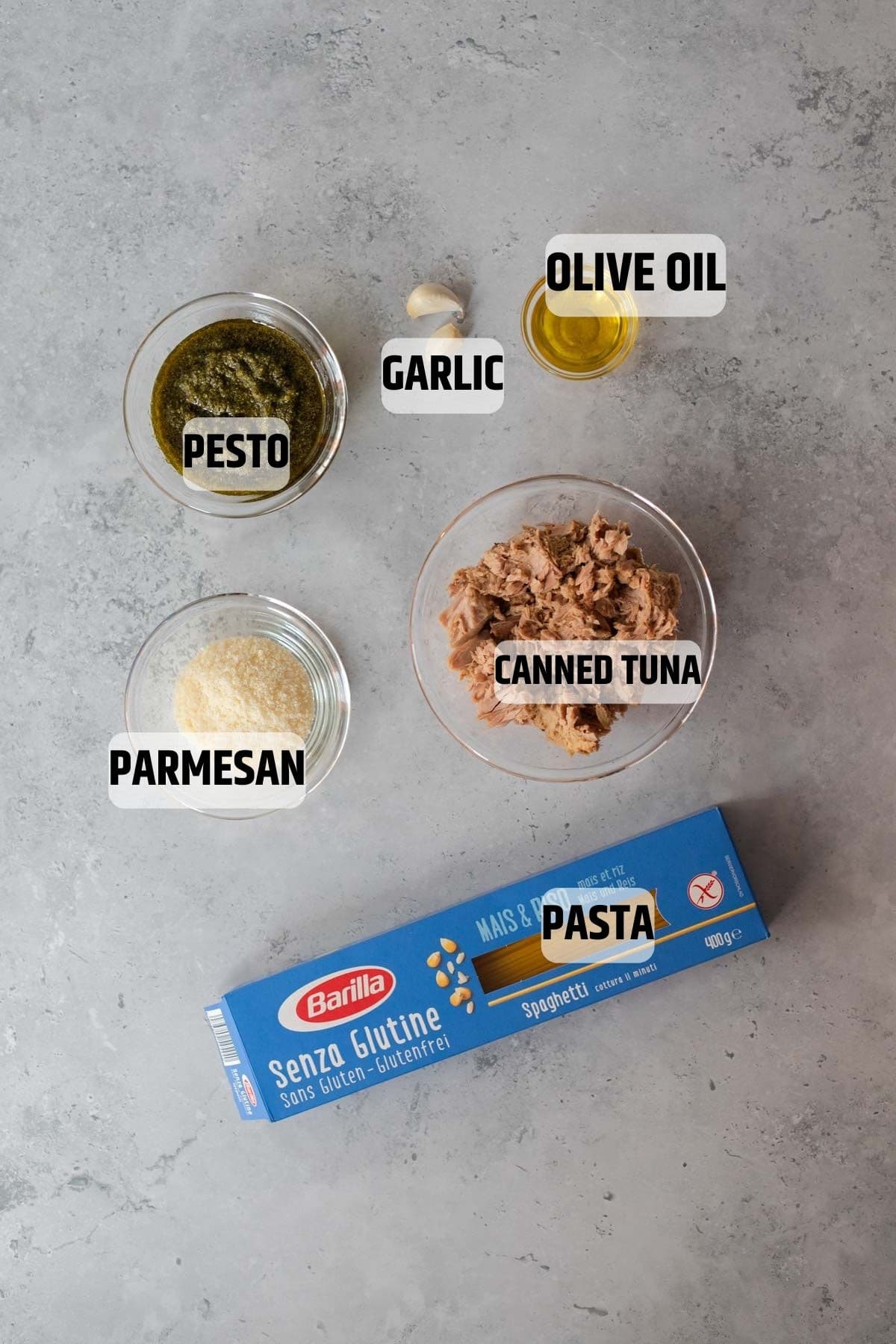 Ingredients for tuna pesto pasta on a grey stone background.