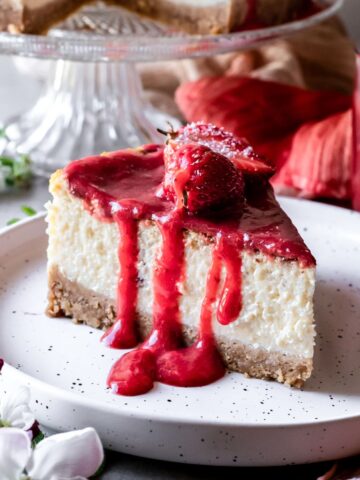 A slice of gluten-free New York style cheesecake with strawberry sauce.