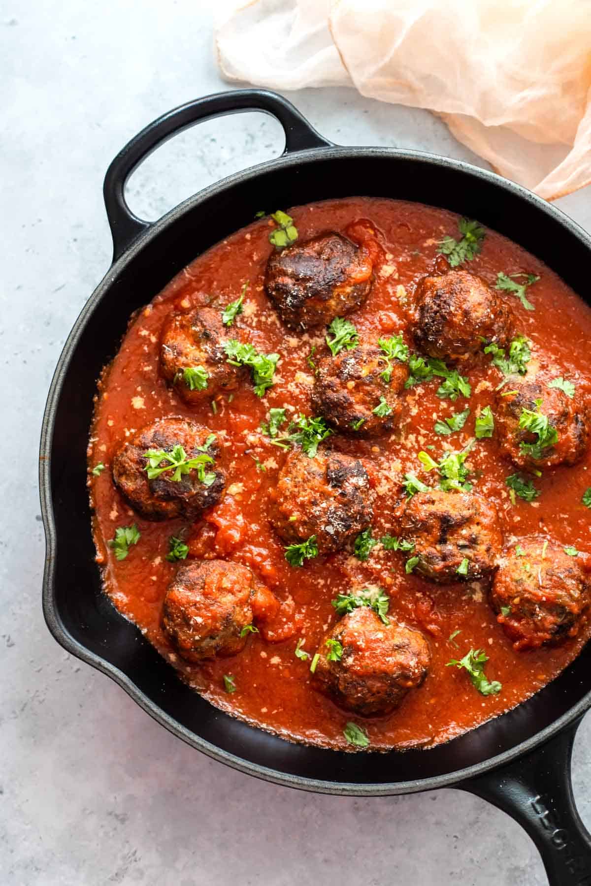 Meatballs in a skillet with tomato sauce.