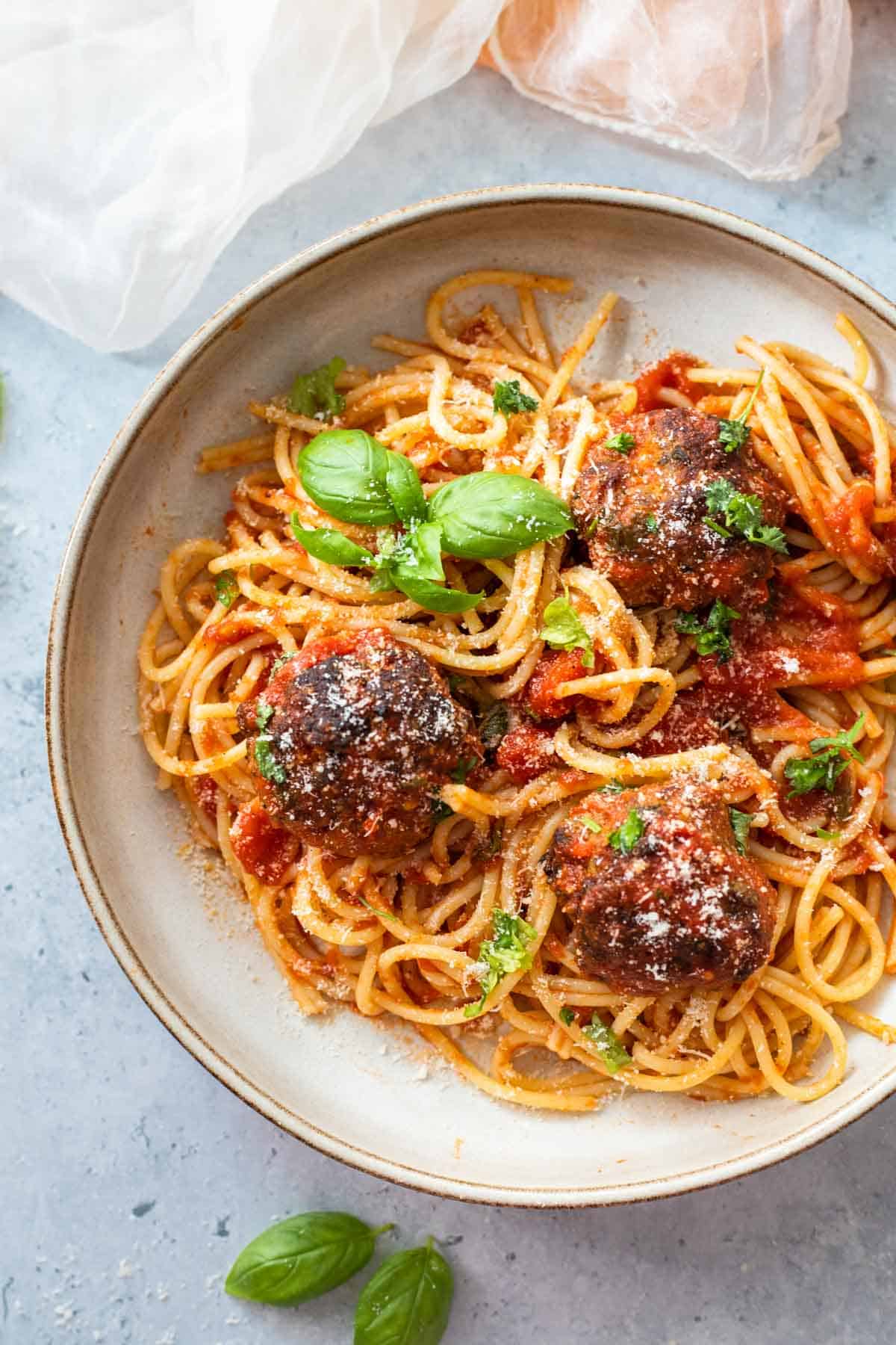 A plate with spaghetti with tomato sauce and meatballs.