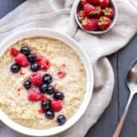 Quinoa Porridge in a bowl topped with raspberries and blueberries.