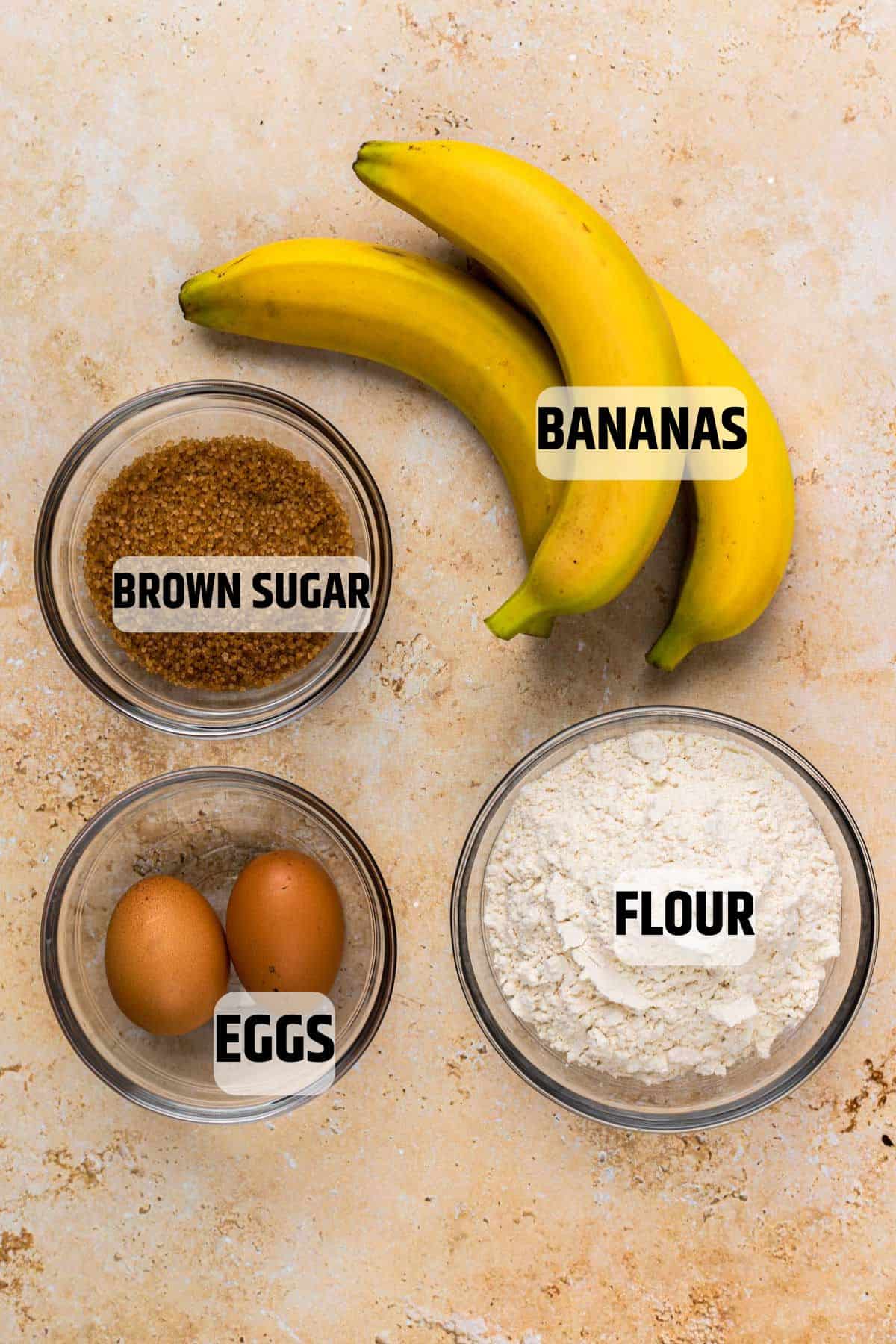 Ingredients for banana bread on a sandstone backdrop.
