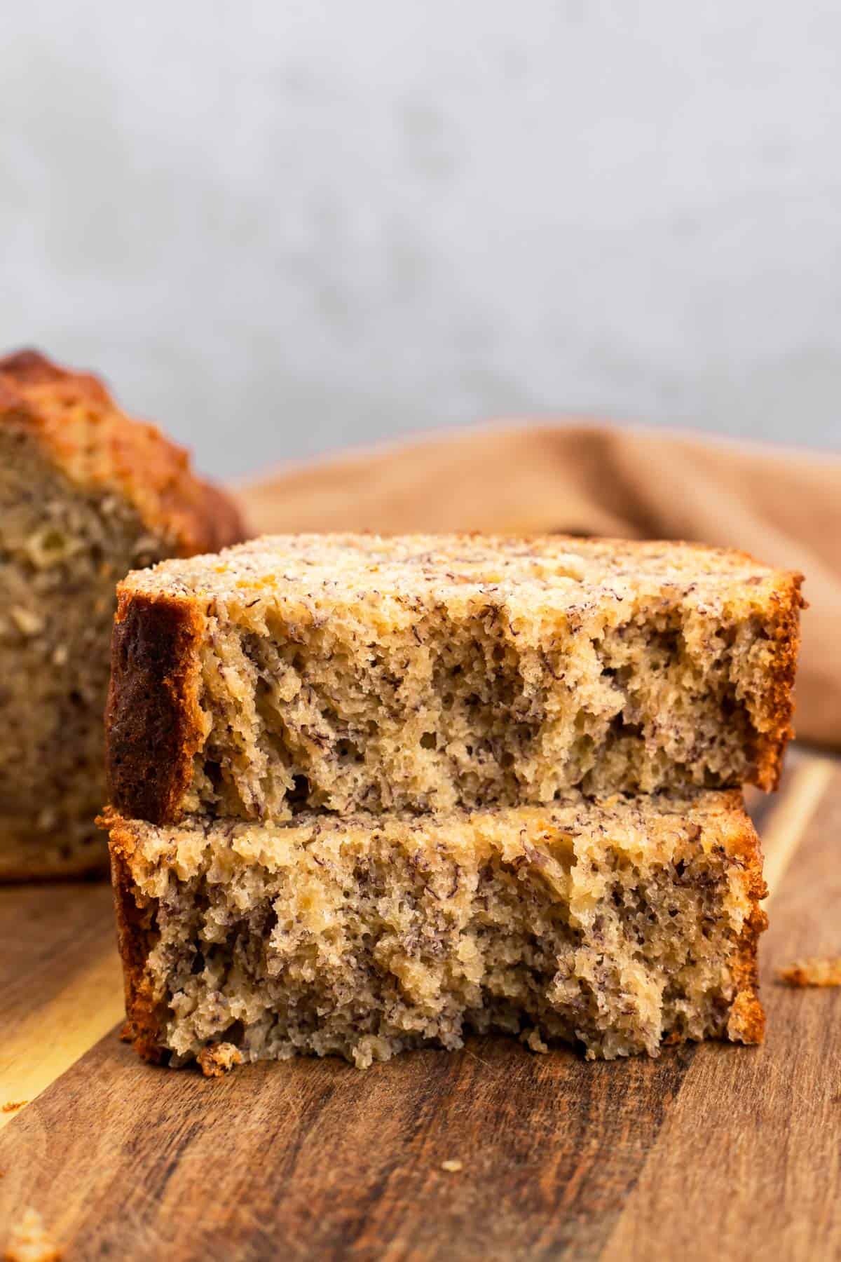 A slice of banana bread broken in two to show the texture.