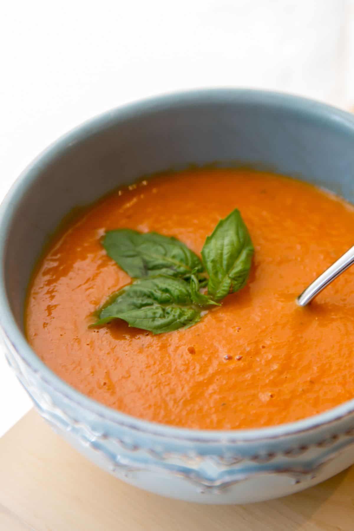 Creamy Sundried Tomato Soup in a bowl decorated with basil.