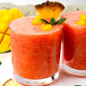 Two glasses of sunrise sunset smoothie decorated with mint and mango.