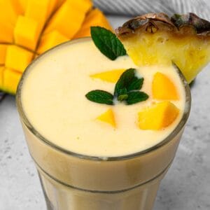 top view looking down at the mango smoothie topped with mango chunks and a pineapple slice