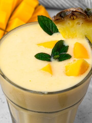 top view looking down at the mango smoothie topped with mango chunks and a pineapple slice
