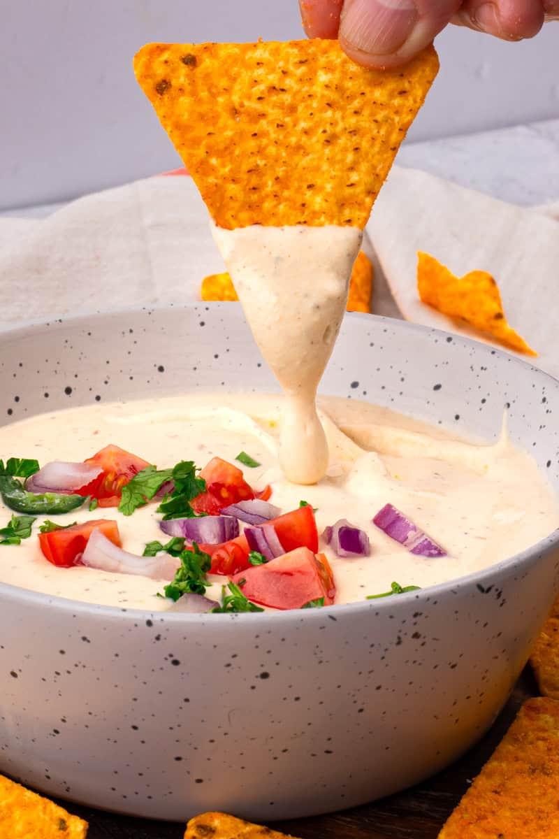 chip dipping into queso dip