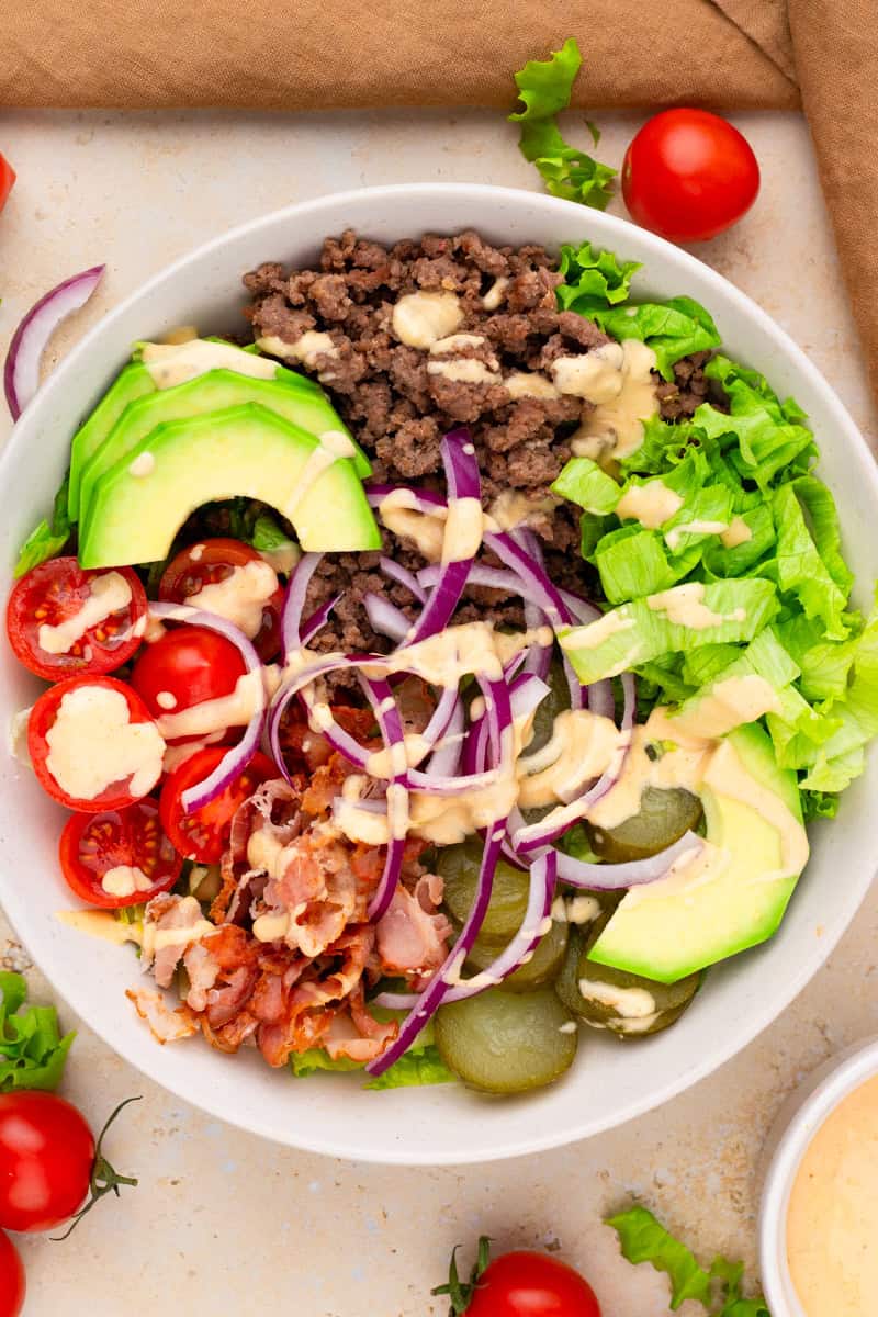 overhead view of burger bowl full of beef, tomatoes, pickles, and other burger toppings