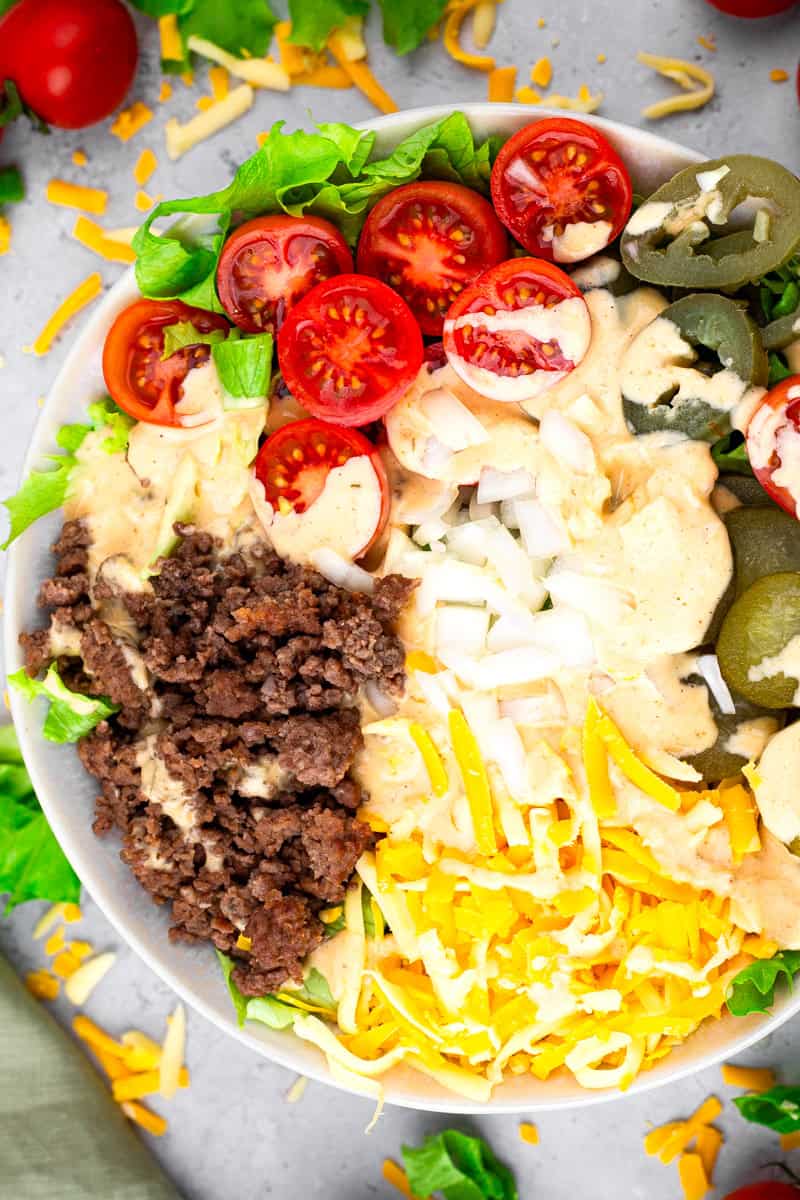 overhead view of cheeseburger bowl recipe in a white bowl filled with beef, cheese, tomatoes, jalapenos