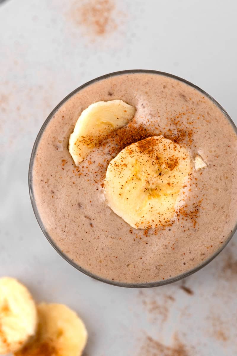 close up of creamy banana smoothie topped with fresh bananas